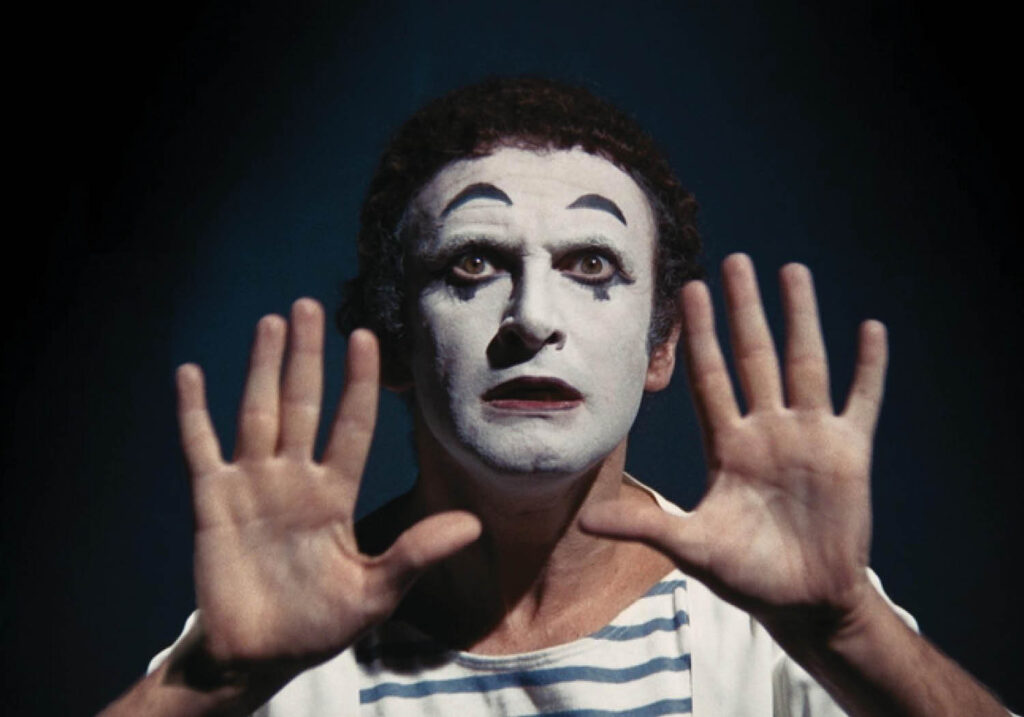Performance portrait of Marcel Marceau in classic white face, striped shirt and exaggerated gesture